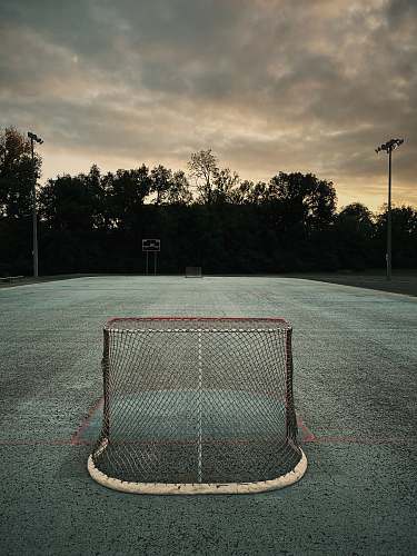 tarmac soccer field near trees under cloudy sky road