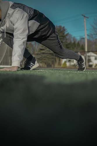 apparel man in grey track pants and jacket with hand on grass footwear