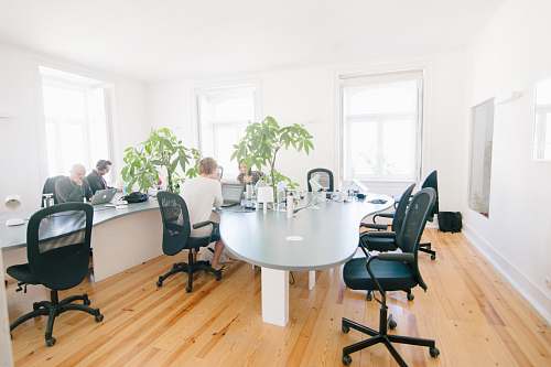 indoors grey wooden table and black leather rolling chairs chair