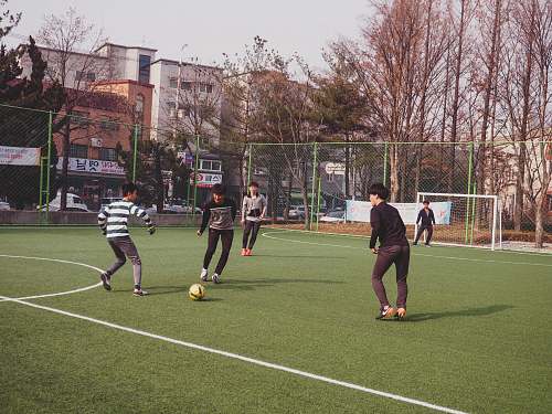 person boys playing soccer on field people