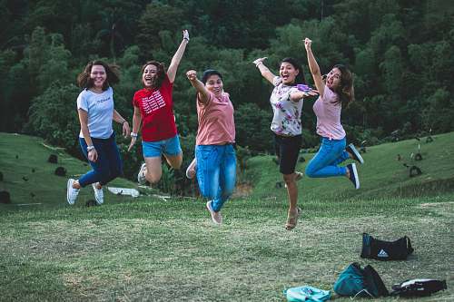 person five women jumping on green grass people