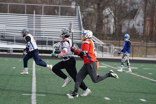 person four men playing lacrosse game during daytime apparel