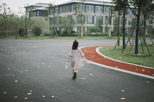 person girl holding clear plastic bottle walking on road people