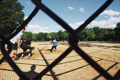 person gray cyclone fence across people playing baseball people