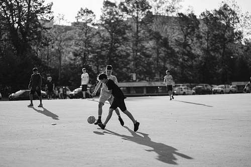 people grayscale photo of group of man playing soccer on field black-and-white