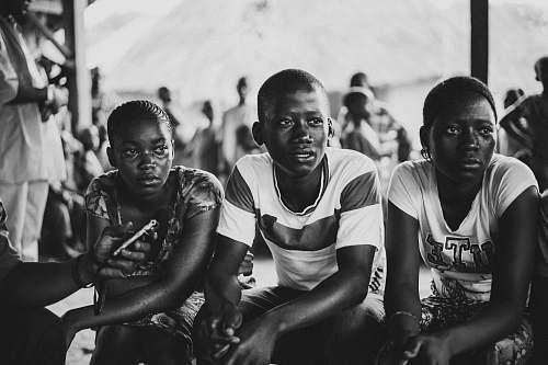 person grayscale photo of three person sitting black-and-white