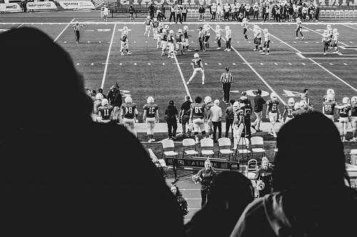 person grayscale photography of group of men playing soccer surrounded with people watching them black-and-white