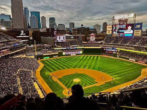 person green and brown baseball stadium with people watching during daytime building