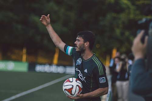 person man in black and green Adidas jersey shirt holding soccer ball soccer