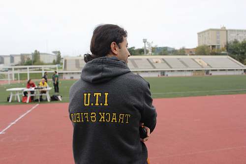 person man in black and yellow hoodie front of field people