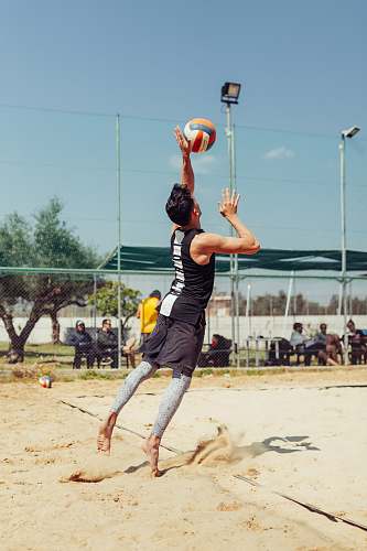 person man in black top playing beach volleyball during daytime sphere