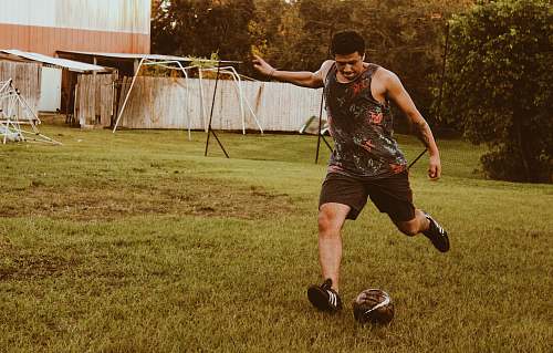 person man kicking football on grass field during daytime apparel