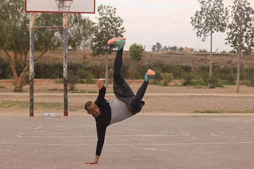 person man making stunt near the basketball hoop outdoor during daytime people