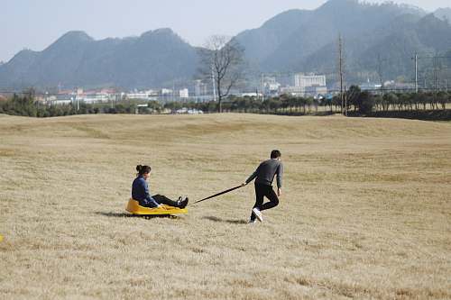 person man pulling wagon with woman riding on it people