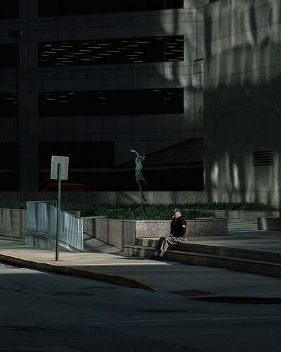 person man sitting on stairs outside building people