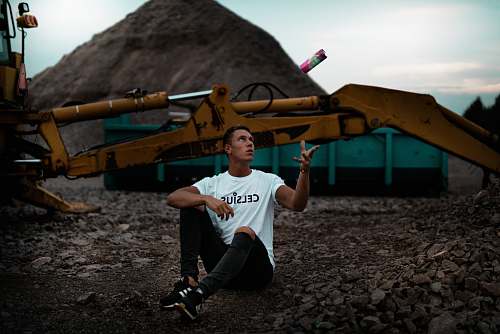 person man sitting on the ground near excavator people