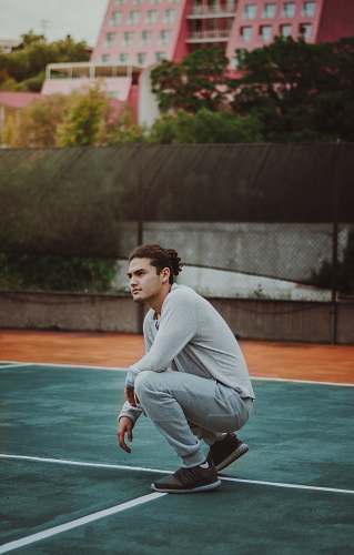 person man squatting on court during day people