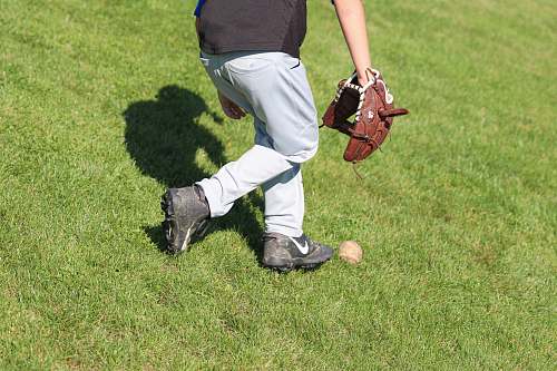 apparel man standing on grass field picking up baseball clothing