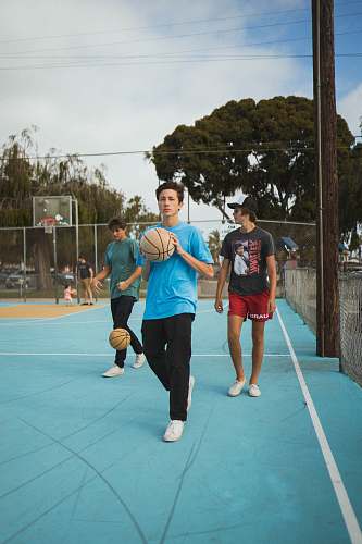 person man wearing blue t-shirt and black pants holding basketball during daytime apparel
