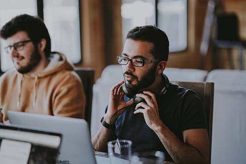 person man wearing eyeglasses and headphones beside smiling man people
