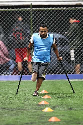 person man wearing gray shirt and black cane playing soccer field