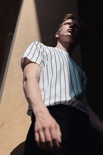 person man wearing white striped shirt leaning on wall apparel