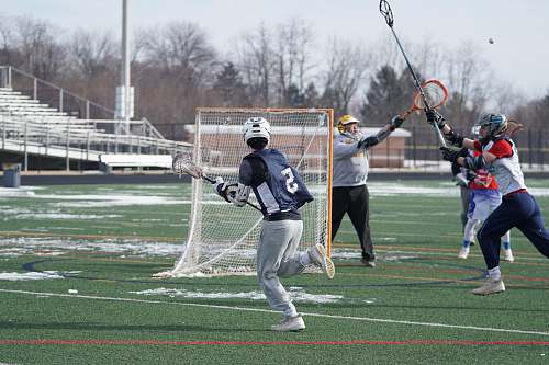 person men playing lacrosse on field with snow people