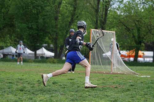 person men playing lacrosse stick near trees at daytime apparel
