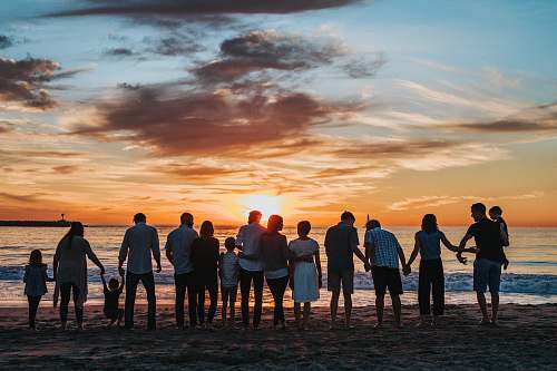 person people standing on shore during golden hour family