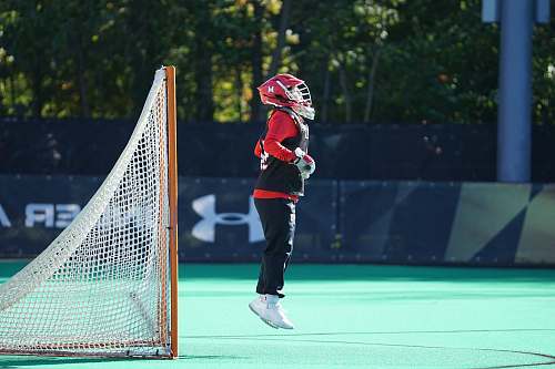 person person jumping wearing red and white head gear in front of net goal apparel