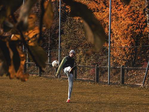 person person kicking white ball on field at daytime people