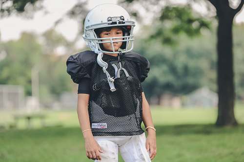 person selective focus photography of boy wearing American football gear people