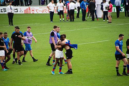 people soccer players and people walking, hugging, and standing at the field person
