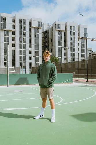 person standing man wearing green pullover hoodie inside court people