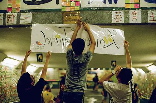 person three men putting signage apparel