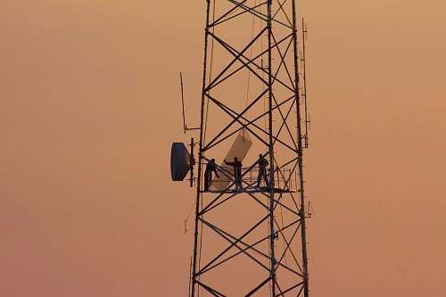person three people standing on crane tower cable