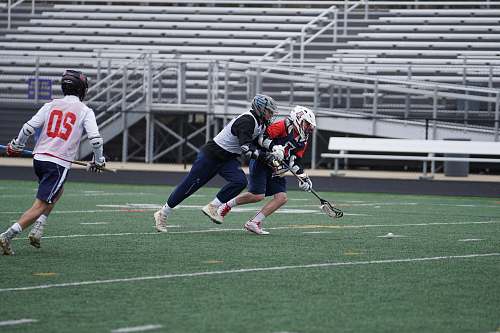 person three person playing lacrosse during daytime apparel