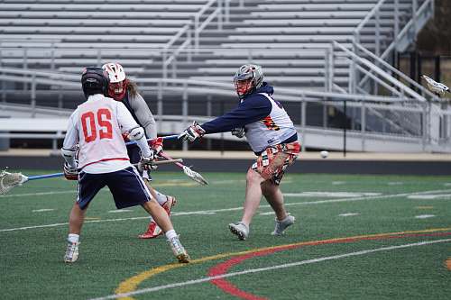apparel three person playing lacrosse on field during daytime clothing