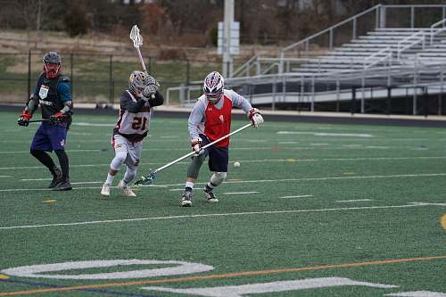 person three person playing lacrosse on field during daytime people