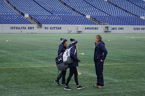 person three women standing on green field while having conversation people