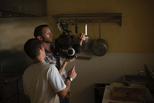 people two men fixing camera inside kitchen person
