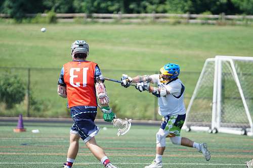 person two men playing lacrosse during daytime apparel