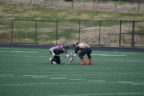person two men playing lacrosse on field people