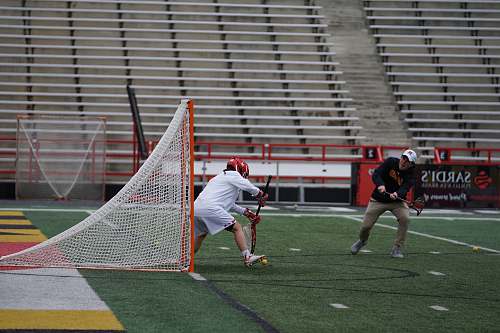 person two men playing lacrosse outside people