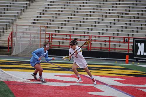 person two women playing lacrosse during daytime apparel