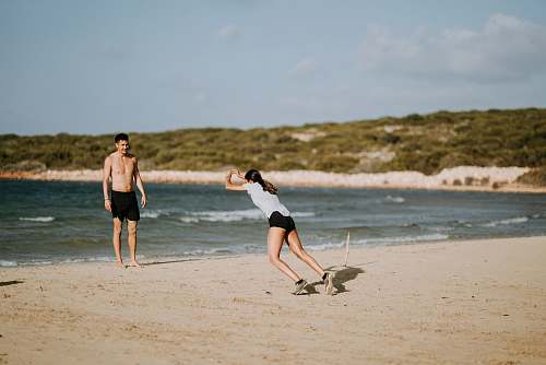 beach woman and man standing near beach line sea