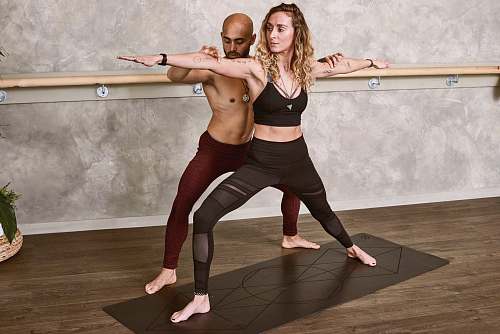 person woman doing yoga assisted with man fitness