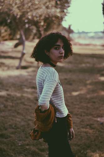 hair woman in white shirt standing near green trees afro hairstyle