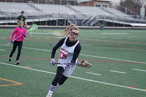 person woman playing lacrosse on green field racket