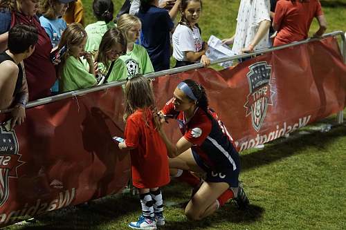 person woman wearing red and black jersey helping little girl people